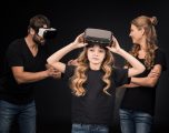 Family with one child wearing virtual reality headsets standing  isolated on black
